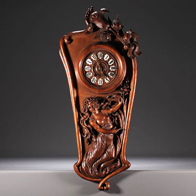 Art Nouveau clock in carved walnut with a half-dressed lady and floral decoration, enamel numerals, circa 1900.