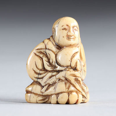 Netsuke carved - a figure holding a fruit, Japan Edo period
