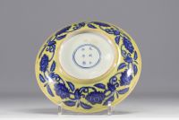 Chine - Plat en porcelaine à décor de fleurs en blanc et bleu sur fond jaune, marque en bleu.