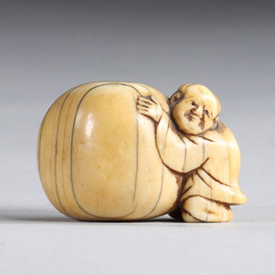 Netsuke sculpté d'un personnage poussant un rocher. Japon époque Meiji 19ème