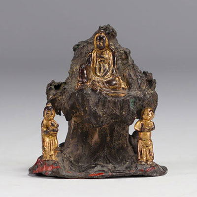 Sculpture Guanine en Bronze assise sur un rocher et entourée de deux personnages.
