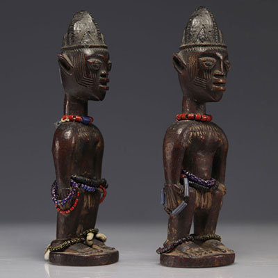 Pair of feminine wooden Ibedji with dark patina decorated with jewels and pearls