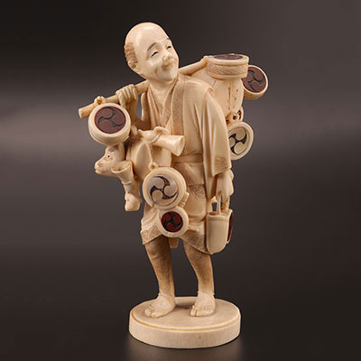 Japon -  Okimono en ivoire, colporteur debout portant des tambours et jouets, partiellement incrustés de corne MEIJI (1868-1912)