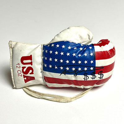 Andy Warhol. Signature au feutre de « Andy Warhol » sur un gant de boxe américain, agrémenté de trois sigles dollar.